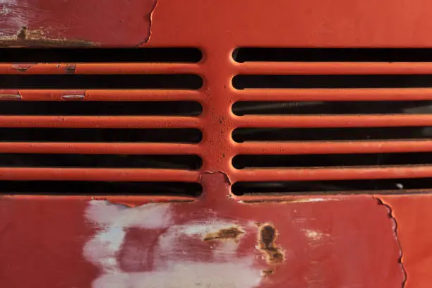 Closeup of rusty aged red car vents retro style old vw beetle rear peeled bright red paint