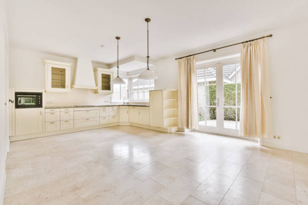 Corner cupboards and table located near glass backyard door in light kitchen of contemporary flat