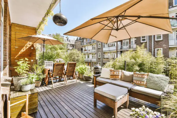 Lounge area with sofa and armchairs and tables under canopy in cozy balcony