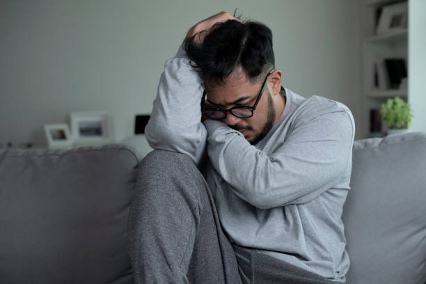 istock Man sitting on couch at home feeling sad, life difficulties. 1409200984