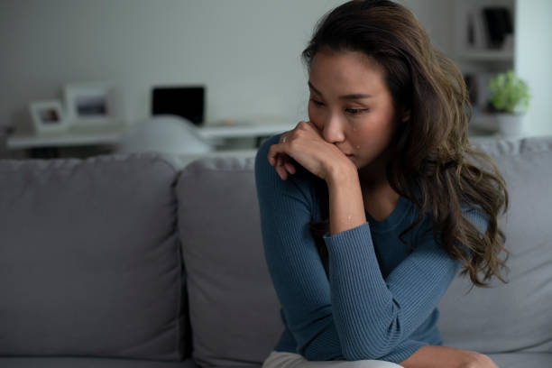 istock Woman sitting on couch at home feeling sad, life difficulties. 1409206281