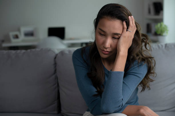 istock Woman sitting on couch at home feeling sad, life difficulties. 1409206282