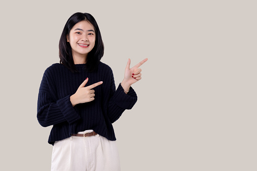Portrait of a Young modern Asian woman standing and looking at camera over isolated background.