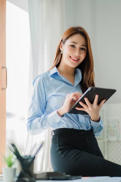 istock Freelance Asian woman working on a computer tablet in a modern office. make an account analysis report on real estate investment information financial system concept and tax vertical picture 1409216017