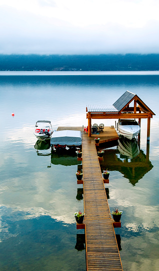 Reflections of cloudy sky in Okanagan Lake, with boats and dock
