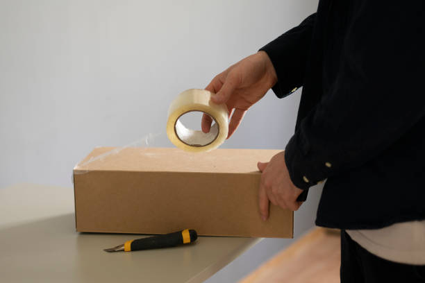 istock person's hands sealing big cardboard box with tape for shipment 1409218514