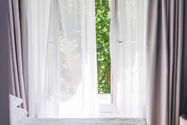 istock White tulle curtains on the window with green trees on background at home 1409218711