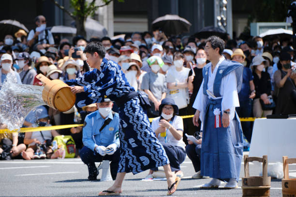 Young man in traditional garb throwing water to prepare to turn a float at the Gion Festival stock photo