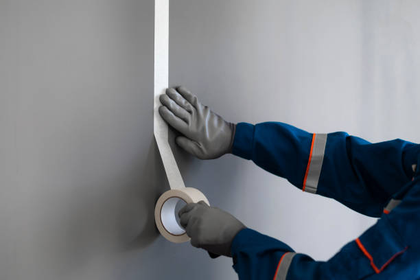 paint worker put masking tape on the wall stock photo
