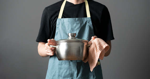 chef in apron cooking dish holding a pot in the kitchen