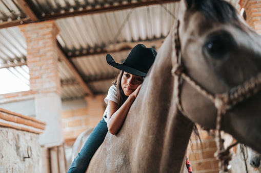 Girl with her horse in the stable, enjoying the day.