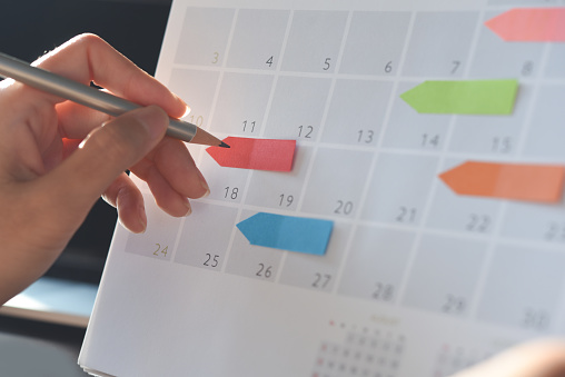 Event planner timetable agenda plan on organize schedule event. Business woman checking planner on mobile phone and taking note on calendar desk on office table. Calendar event plan, work planning concept