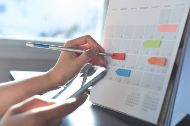 istock Event planner timetable agenda plan on organize schedule event. Business woman using mobile phone and taking note on calendar desk on office table 1409232360
