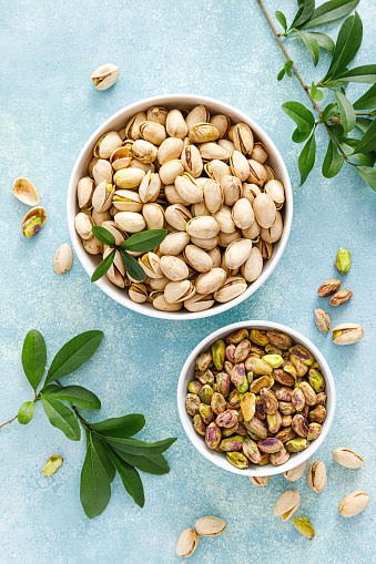 Pistachios. Whole pistachios with green leaves and pistachio nut kernels. Healthy natural vegetarian organic food. Top view, copy space