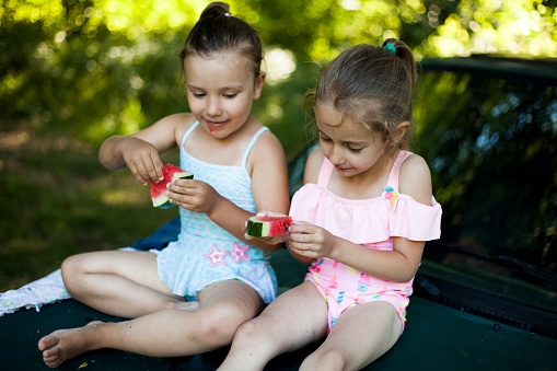 girls eating watermelon outdoors