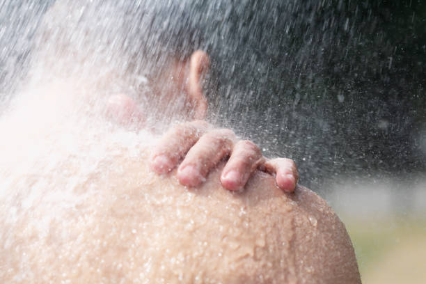 istock Close up: shoulder of a man showering outdoors in summer 1409240074