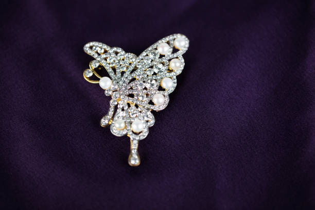 spilla di perle e diamanti a forma di farfalla isolata su uno sfondo di seta viola - brooch jewelry antique gem foto e immagini stock