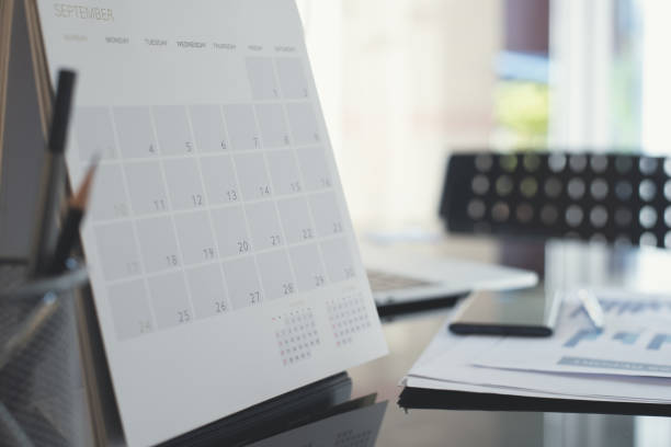 istock Office workspace with desktop calendar, laptop computer and business document on glass table of modern office 1409248468