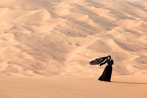 Young woman with a traditional emirati abaya in desert. Abu Dhabi, UAE.