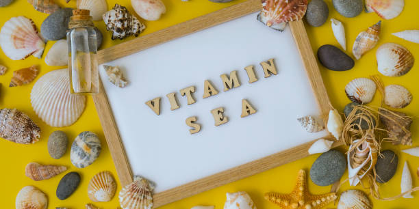 istock Composition sheet white paper text VITAMIN SEA, seashells, pebbles, mockup on yellow background. Blank, top view, still life, flat lay. sea vacation travel concept tourism and resorts. 1409248932