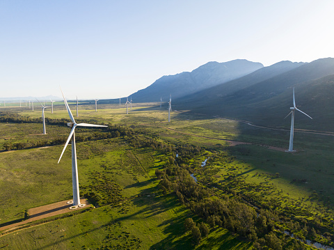 River running between two wind turbines with mountains in background