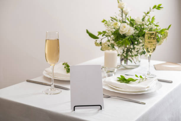 istock Mockup white blank space card for table number or menu. Wedding table decoration with white flowers, glasses and white napkins. Elegantly decorated table at a wedding reception. Festive table setting. The wedding decor. 1409253727