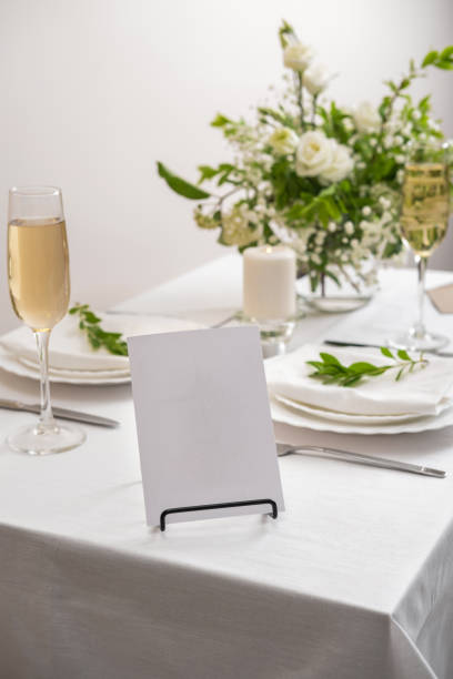 istock Mockup white blank space card for table number or menu. Wedding table decoration with white flowers, glasses and white napkins. Elegantly decorated table at a wedding reception. Festive table setting. The wedding decor. 1409253740