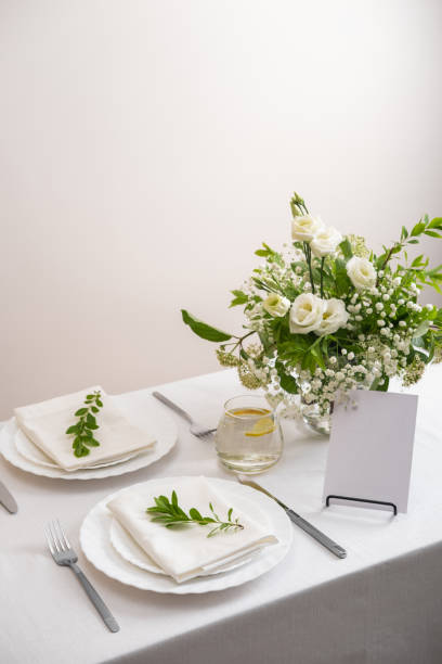 istock Mockup white blank space card for table number or menu. Wedding table decoration with white flowers, glasses and white napkins. Elegantly decorated table at a wedding reception. Festive table setting. The wedding decor. 1409253745