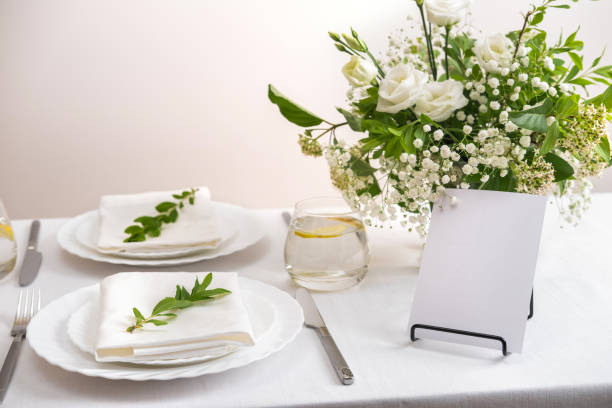 istock Mockup white blank space card for table number or menu. Wedding table decoration with white flowers, glasses and white napkins. Elegantly decorated table at a wedding reception. Festive table setting. 1409253750