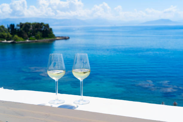 istock Two glasses of white wine with Corfu in background 1409256913