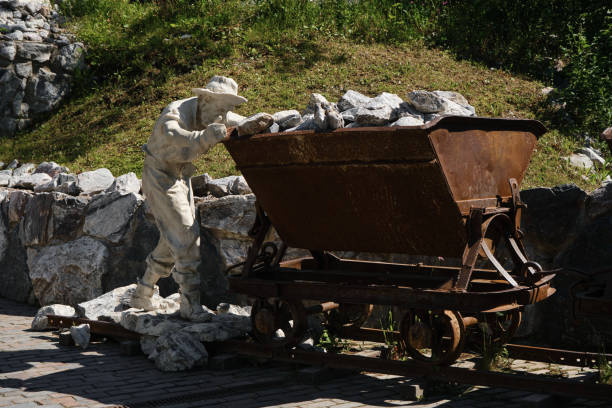 pomnik pracownika górnictwa. człowiek pcha zardzewiały stary wózek z marmurem w środku wzdłuż szyn. ruskeala mountain park, karelia. popularne miejsce turystyczne. - mine worker zdjęcia i obrazy z banku zdjęć