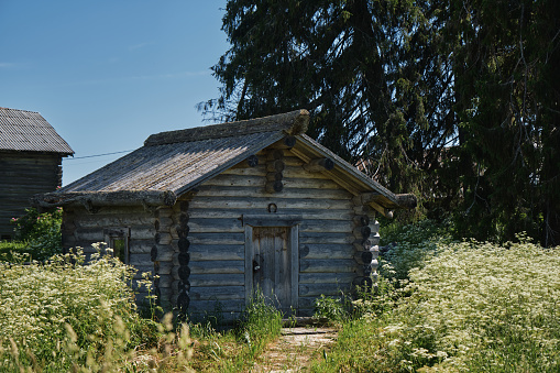 The concept of travel in Russia. One of the most beautiful villages of Karelia Kinerma in summer. The old wooden house has been well preserved to our time. A small barn or storage.