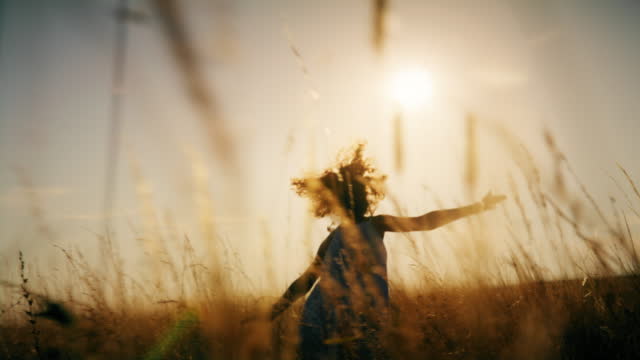 SLO MO Girl runs with arms outstretched in the meadow at dusk