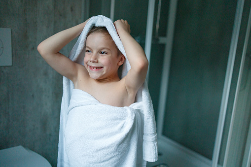 Happy boy drying himself with a towel after shower in the bathroom