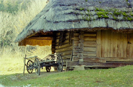 Photo on theme of old wooden hut without windows in abandoned village with cart for horse