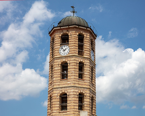 Agios Stefanos metropolitan church historic imposing belfry building, Greece, religious destination Arnaia Halkidiki. Bell tower with cross, weather vane and clock