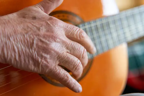 Hand of elderly person playing guitar
