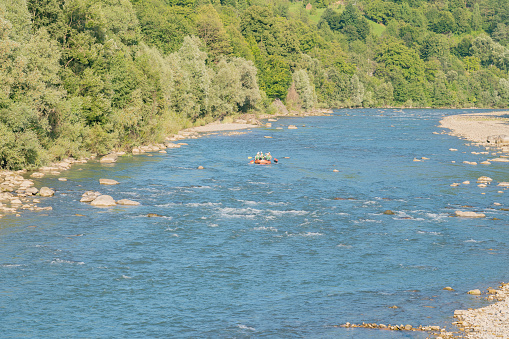 A group of tourists descends on a mountain river on an inflatable boat