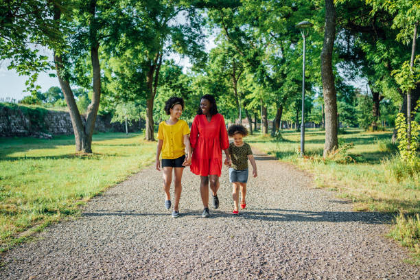 istock Mother with her daughters walking in public park 1409268889
