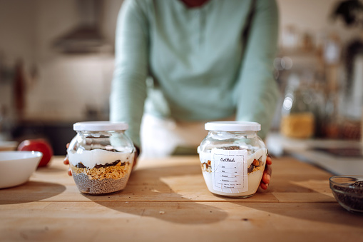 Young unrecognizable woman showing labeled jars with oat meals