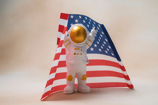 Happy astronaut standing with raised hands on usa flag background