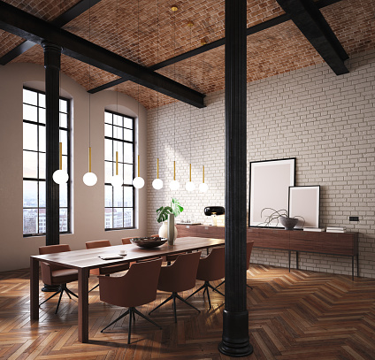 Large table in the central part with brown armchairs. White brick wall and parquet floor. Details in large columns in black. Windows illuminating the room with natural light