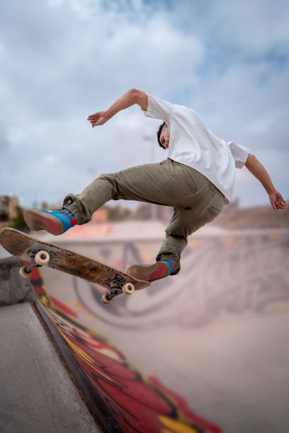 giovane skateboarder fa un trucco chiamato "fakie noseblunt" in uno skate park. composizione verticale - fakie foto e immagini stock
