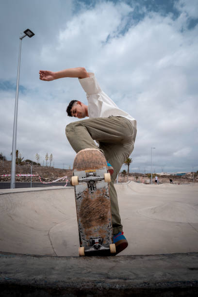 giovane skateboarder fa un trucco chiamato "fakie noseblunt" in uno skate park. composizione verticale - fakie foto e immagini stock