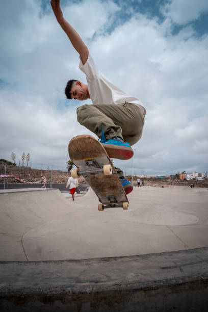 giovane skateboarder fa un trucco chiamato "fakie noseblunt" in uno skate park. composizione verticale - fakie foto e immagini stock