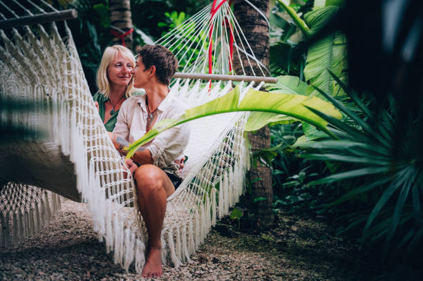 istock Couple sitting in hammock surrounded by tropical trees 1409283110