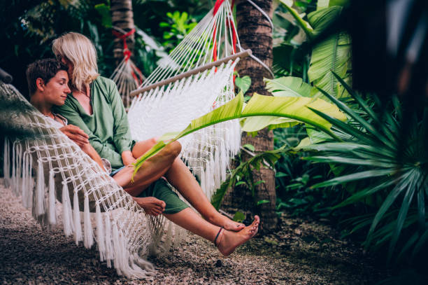 istock Couple enjoy their love while relaxing in a hammock surrounded by tropical trees 1409283158