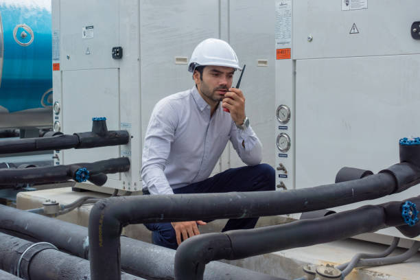 Engineer under checking the industry chilled water fan coil unit air conditioner is water cooling tower air chiller HVAC system of large industrial building to control air system