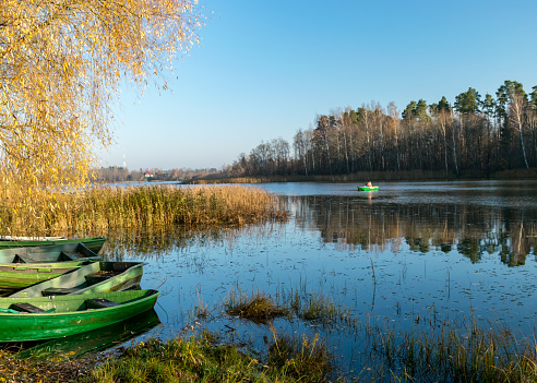 autumn landscape with a small lake, boats on the lake shore, beautiful birch with yellow leaves, fishing concept