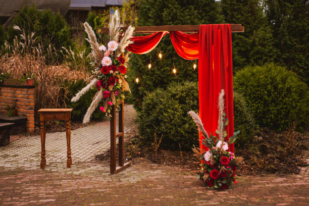 Wedding arch in boho style with flowers and light bulbs. Autumn wedding ceremony. Decor. Rustic